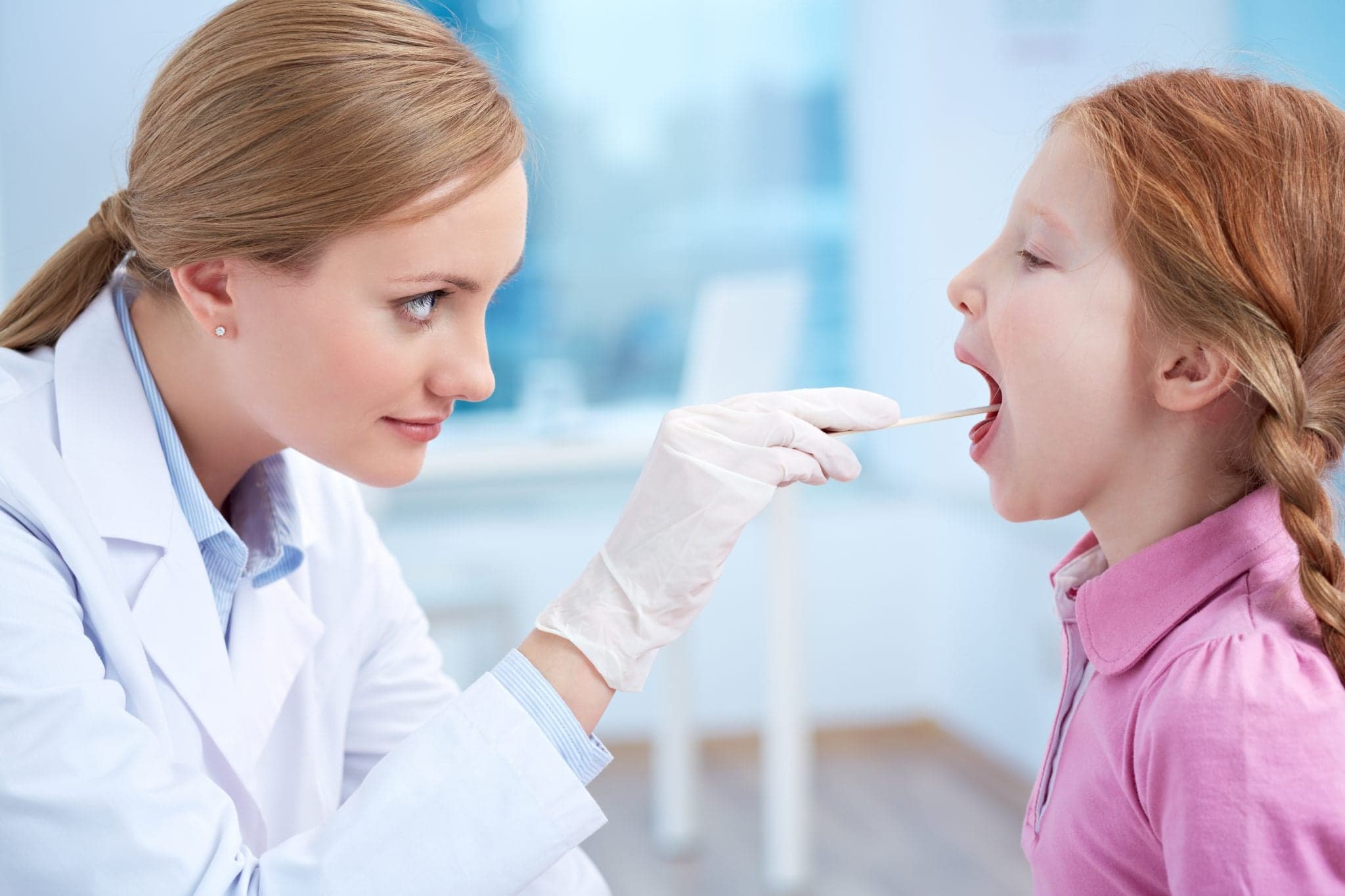 Female doctor examining a little girl's throat