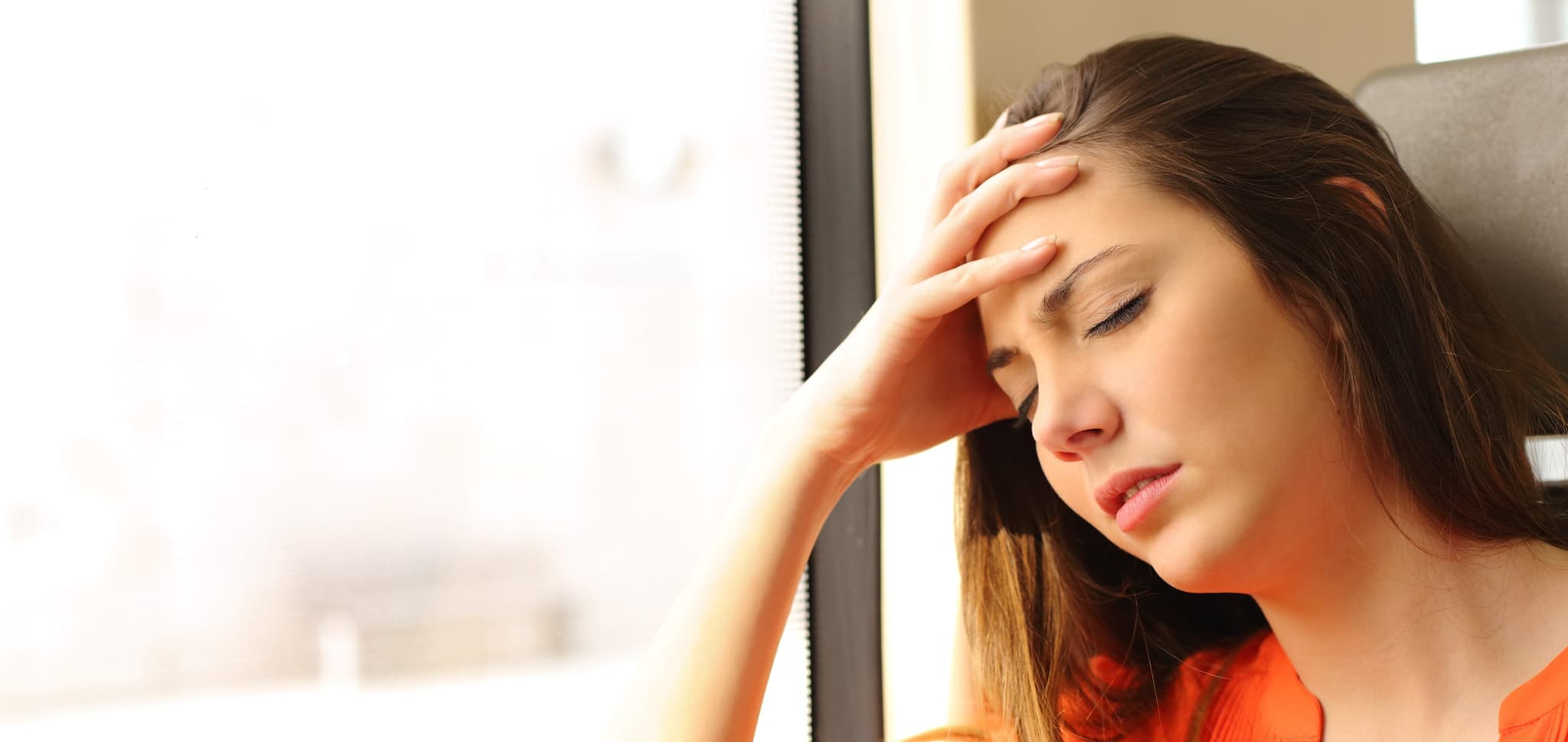 Picture of woman with headache on train leaning against window