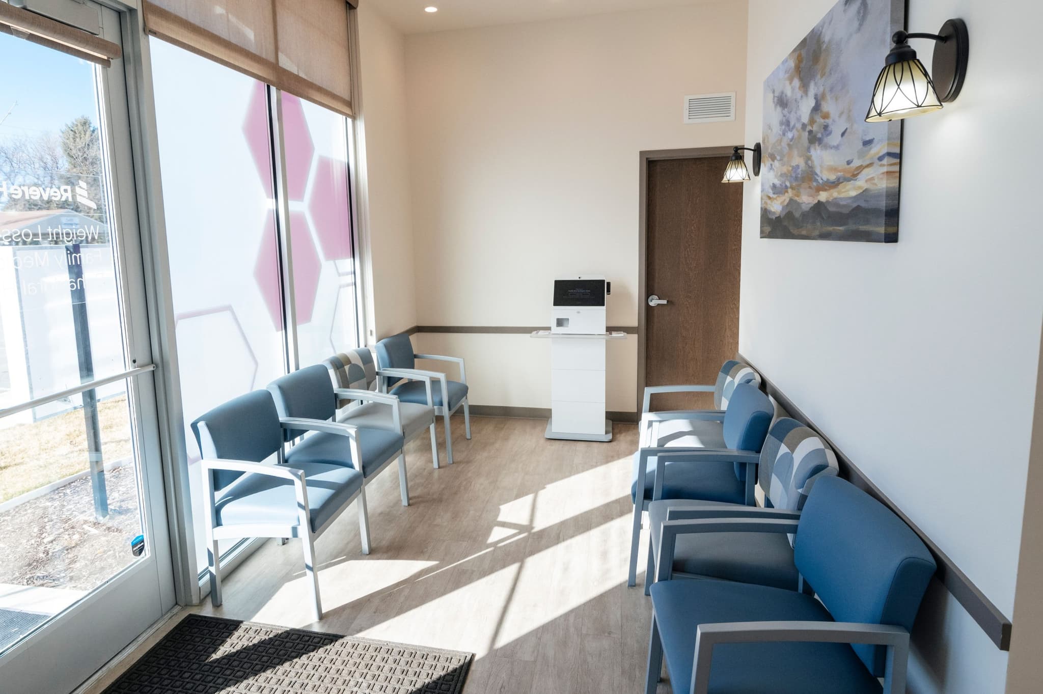 Waiting room with large windows and blue chairs, offering a welcoming space for patients.