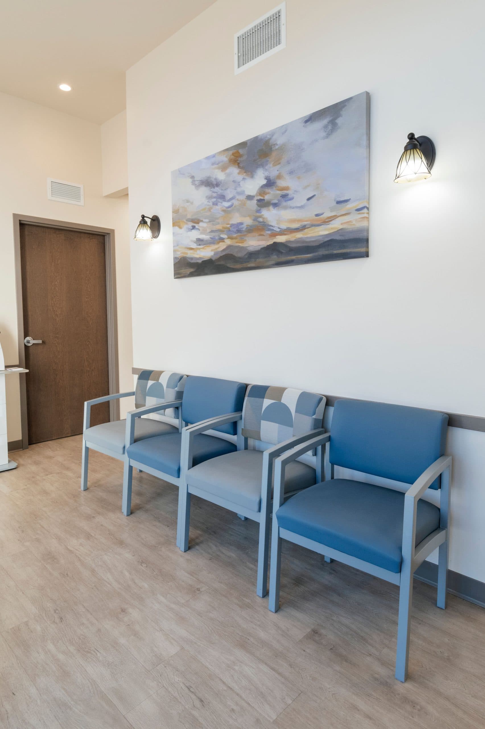 Waiting area with blue chairs and calming wall art, creating a comfortable atmosphere.