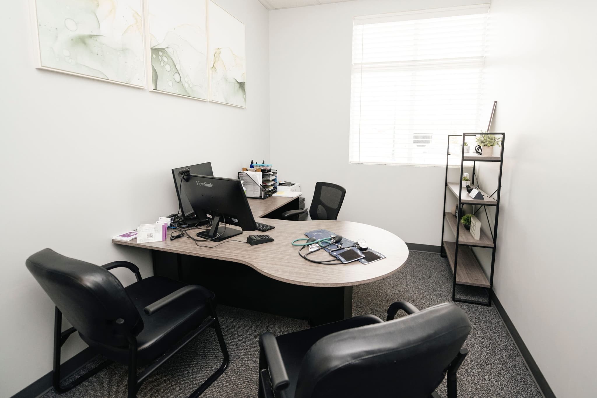 Image of Private office space with a round meeting table, two office chairs, a computer workstation, and soft lighting.