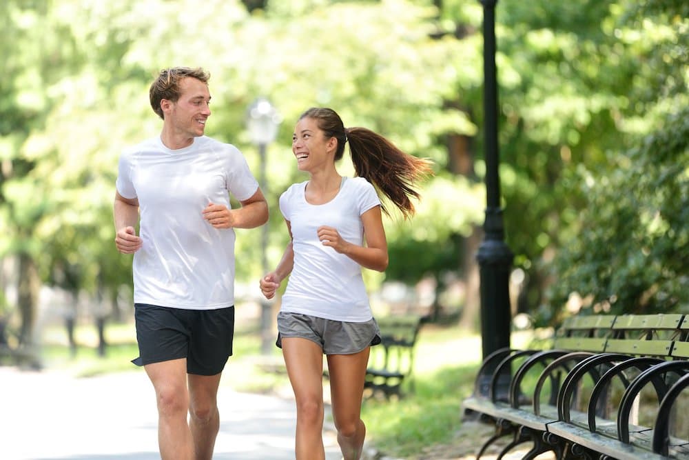 Picture of Runners jogging together in New York City Central Park, USA. Healthy couple of new yorkers athletes friends running in summer sun working out a cardio exercise on Manhattan, United Sates of America.