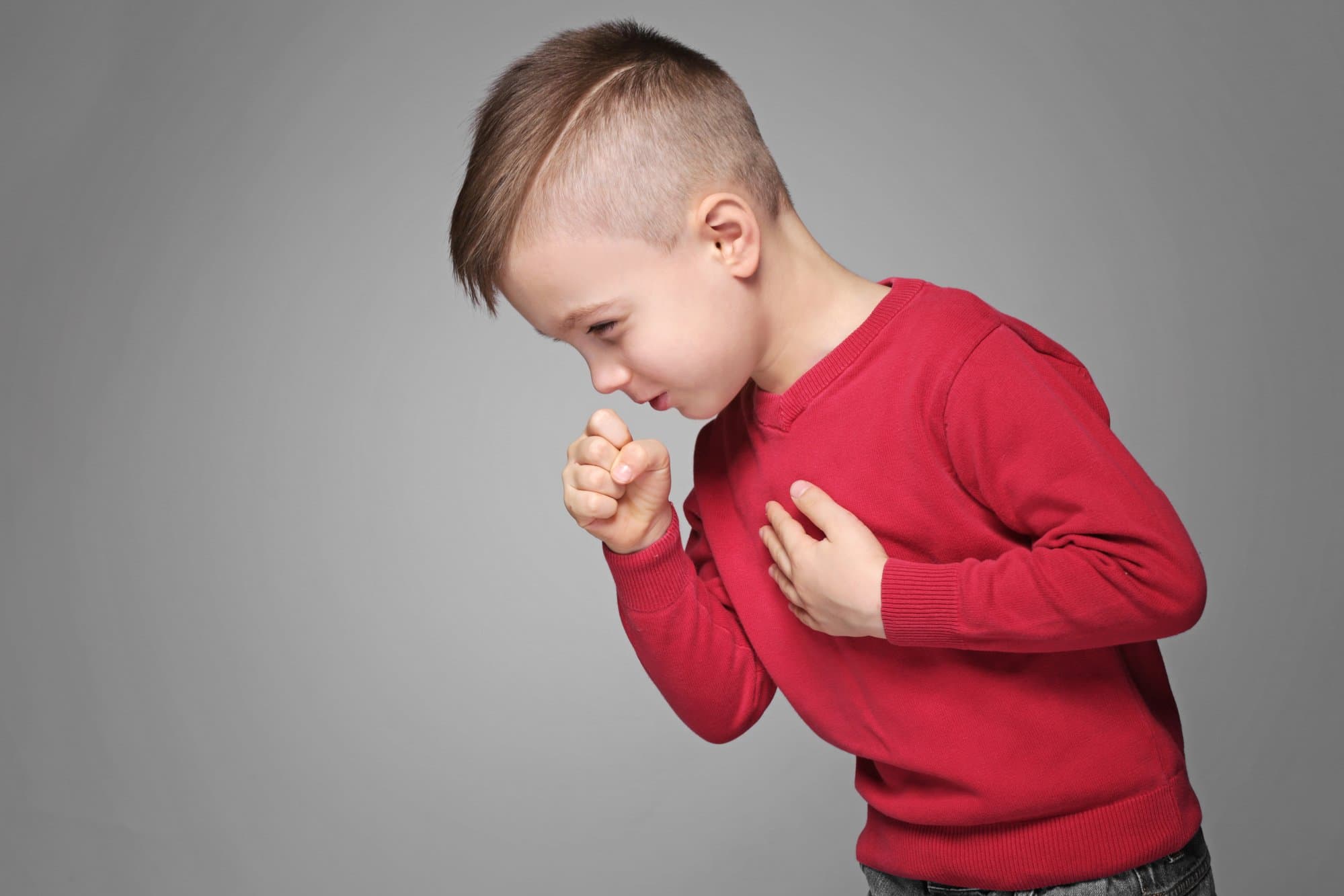 Picture of Cute little boy coughing on gray background