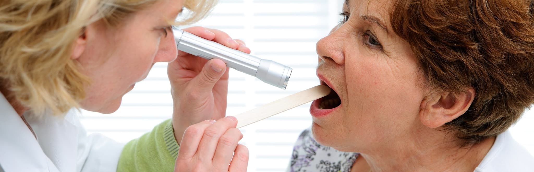 Picture of doctor checking mature woman for Tonsillitis