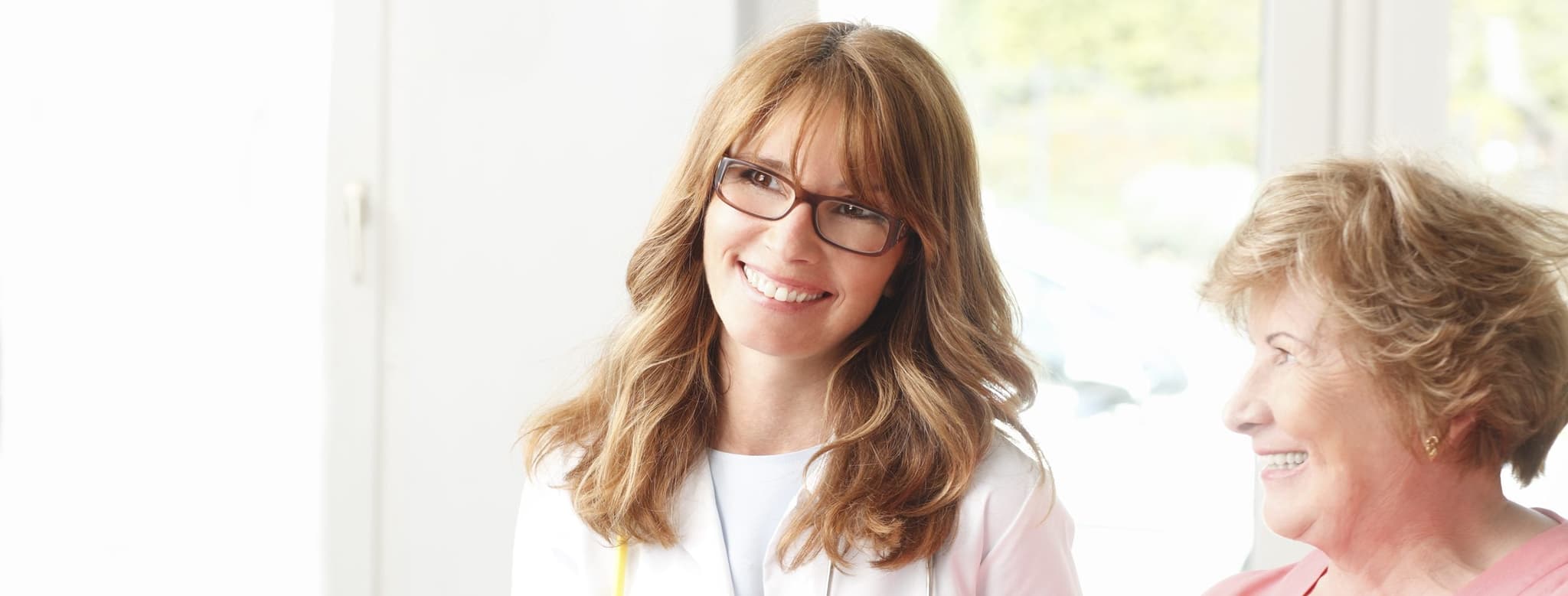 Picture of smiling doctor with clipboard talking to mature patient