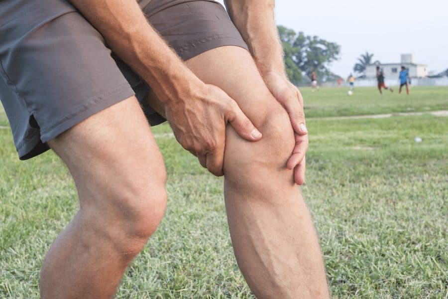man clutching knee in pain on soccer field