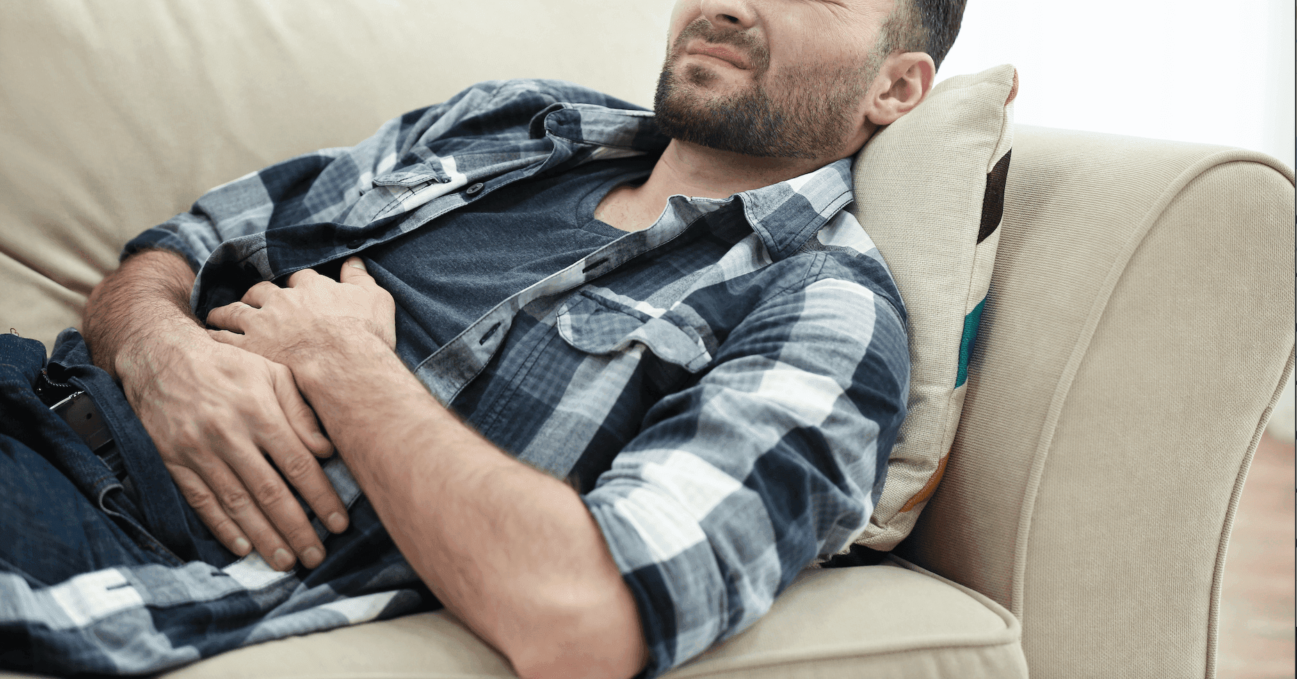 Picture of man laying down holds stomach in pain