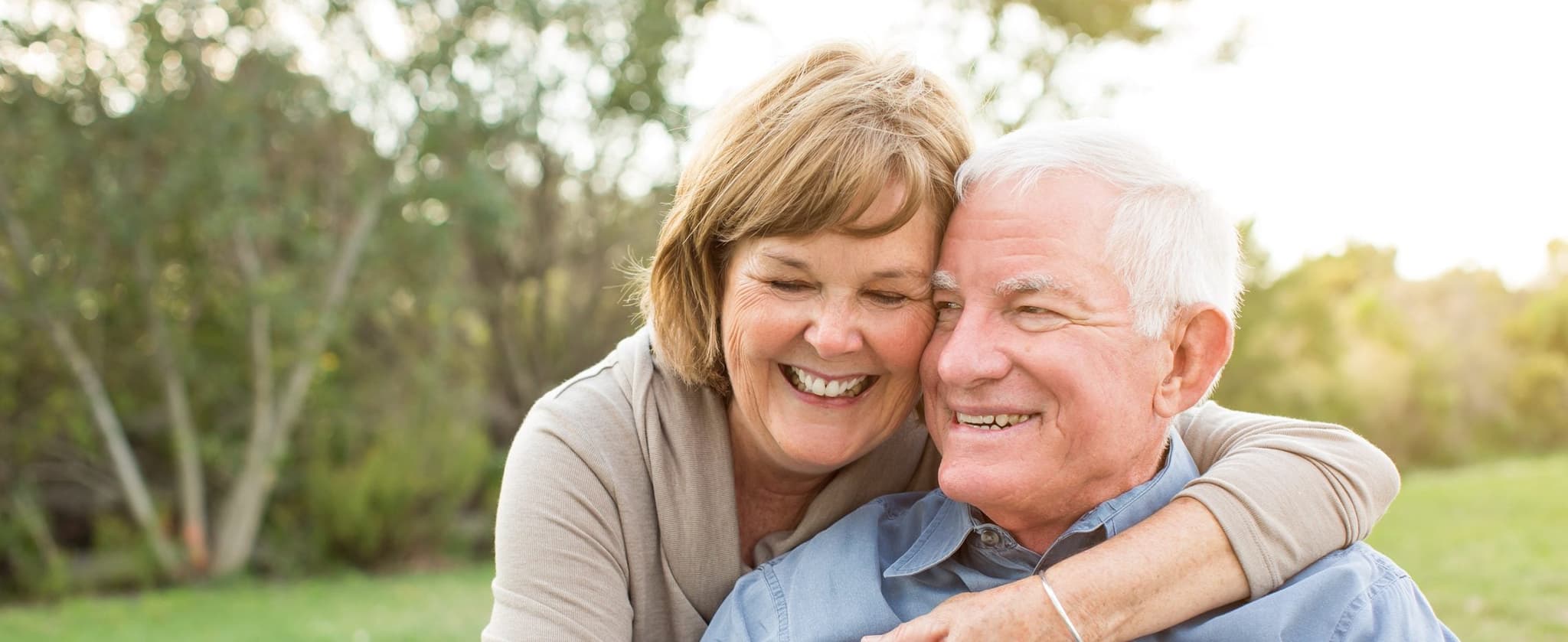 Picture of happy older couple hugging in park