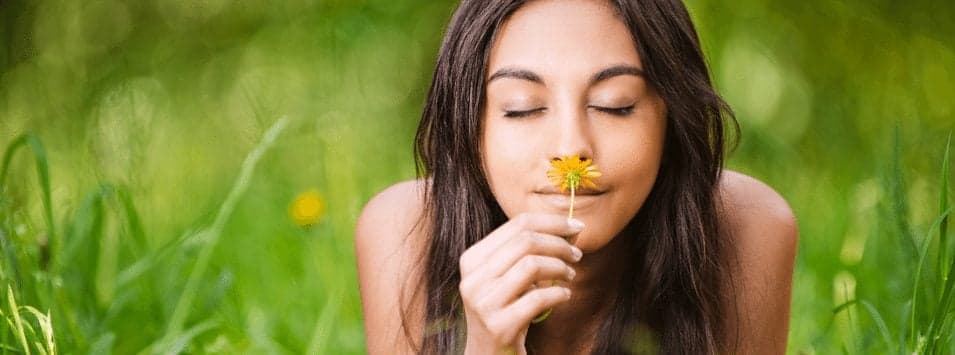Picture of woman smelling flower in grassy field