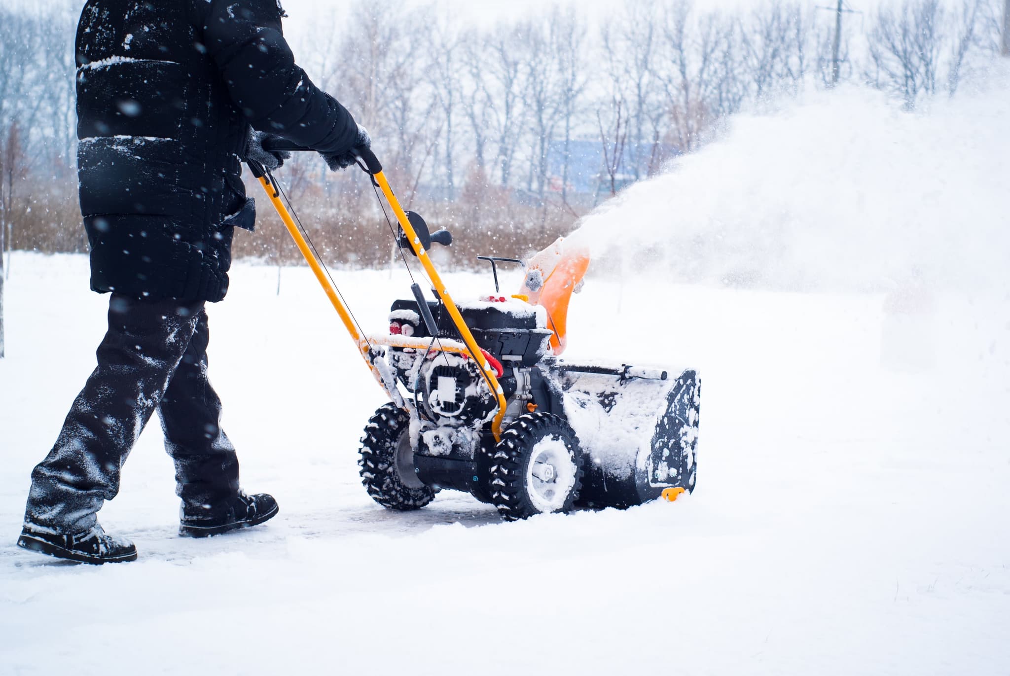 Picture of A man cleans snow from sidewalks with snowblower.
