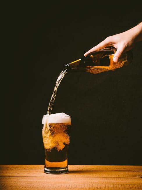 person pouring cup of beer