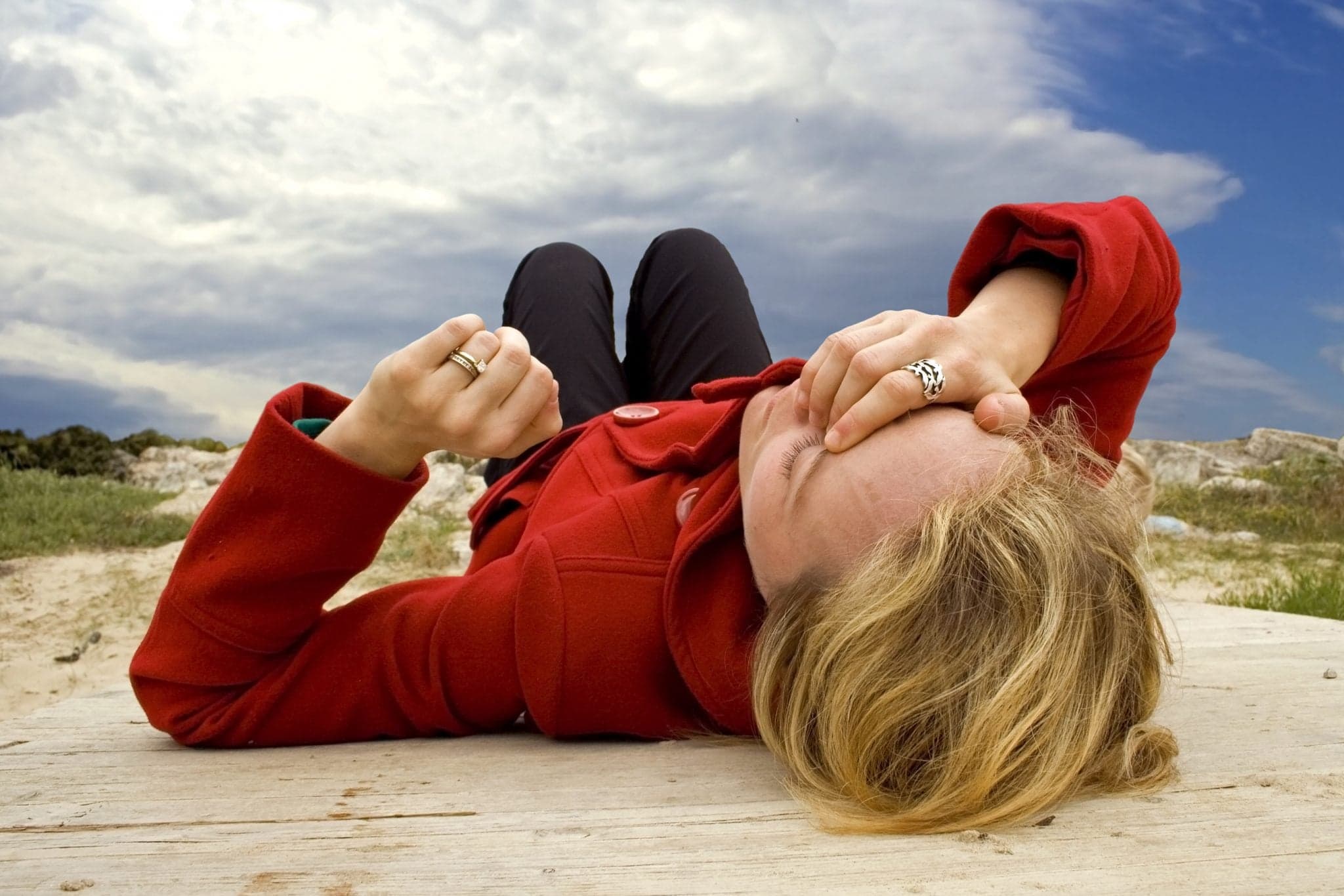 woman lying the the ground outside clutching head in pain