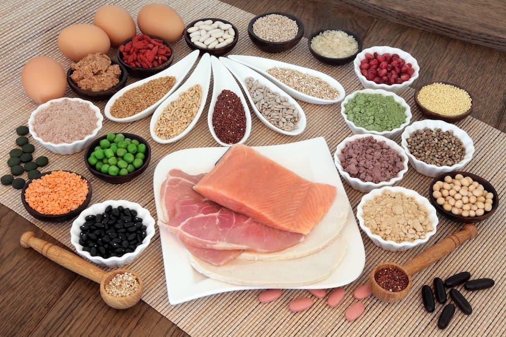 Picture of Body building health and super food with high protein meat, fish, eggs, pulses, seeds, nuts, grains, supplement powders, vitamin tablets and fruit.