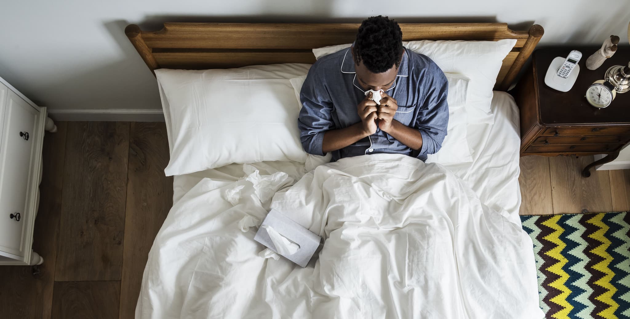 Picture of Sick man on bed blowing his nose