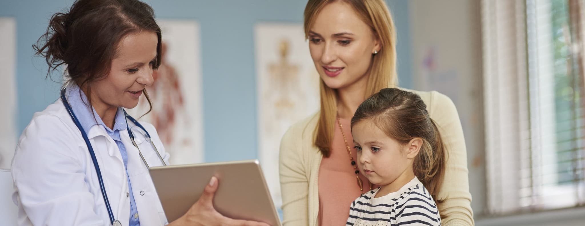 doctor showing ipad results to mother and child