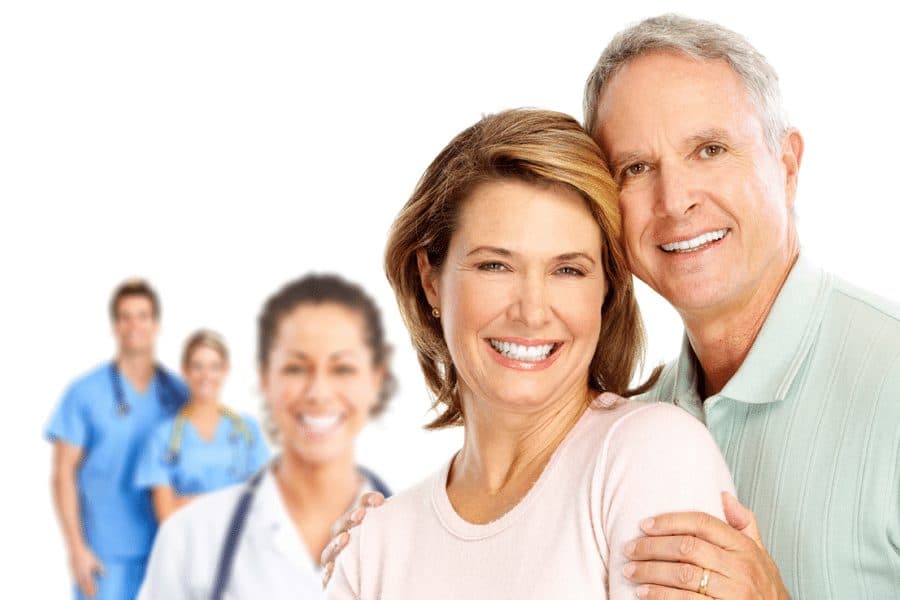 smiling couple with doctors in background