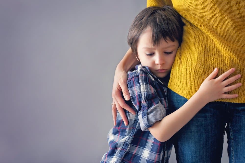 Sad little child, boy, hugging his mother at home, isolated image, copy space. Family concept