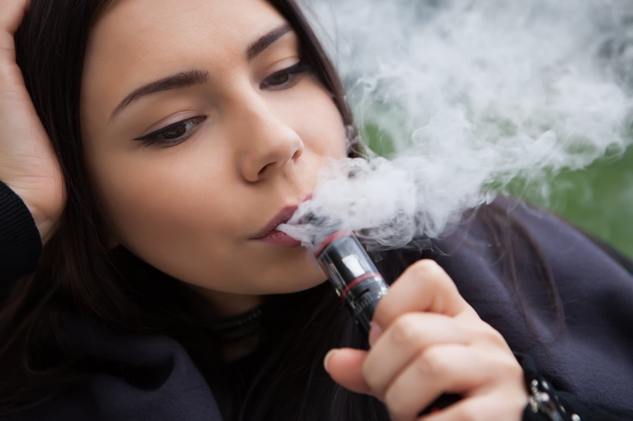 Picture of Quit smoking nicotine, start vaping e-juice, e-liquid. Pretty young woman using vaporizer device, modern gadget for smokers. Safe and tasty glycerin vapor