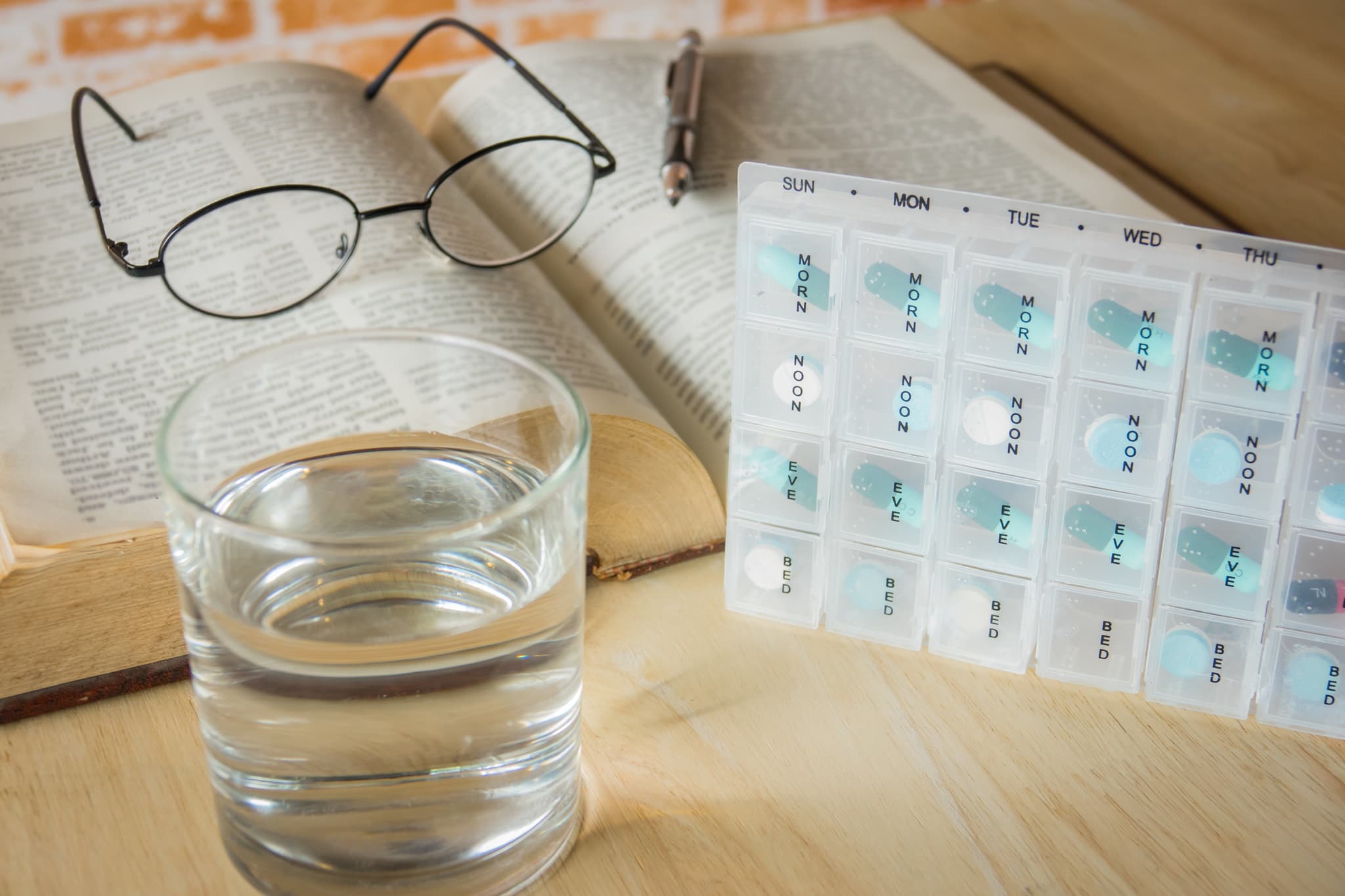 Pills box for week and separate the time with medicine and book on table