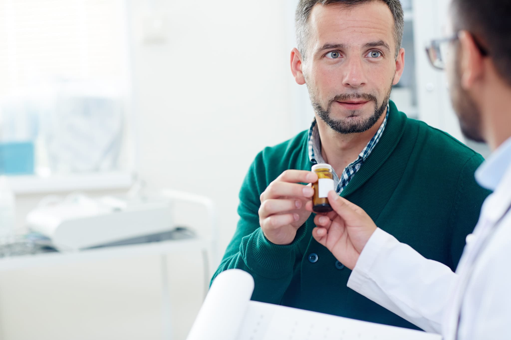 Picture of Sick man taking bottle with medication offered by his doctor in hospital