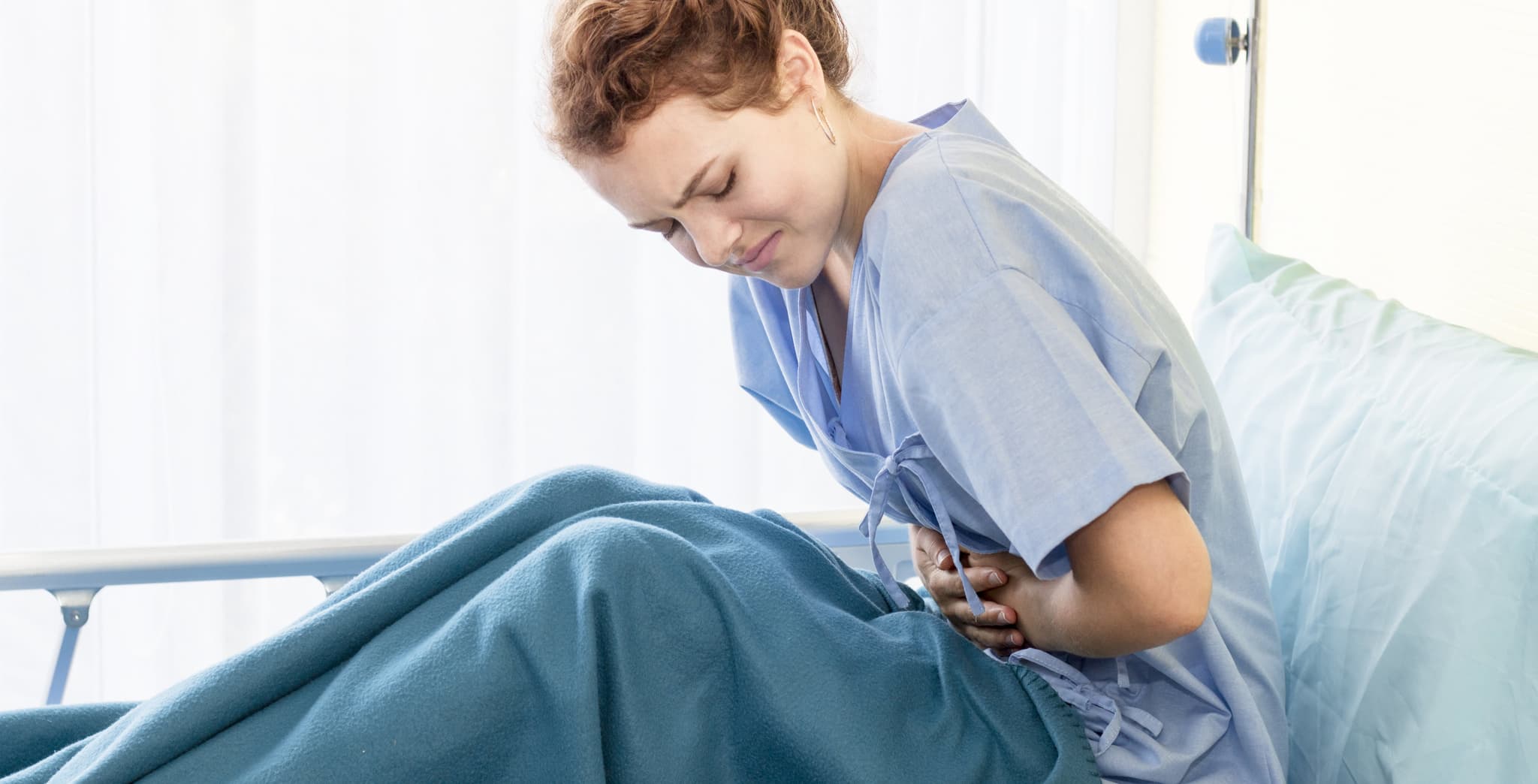 Beautiful young woman patient with period pain on hospital bed room