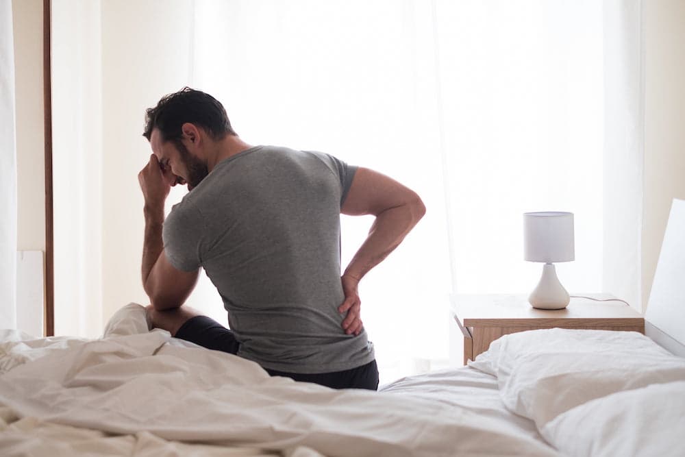 Man feeling backache after sleeping in bed