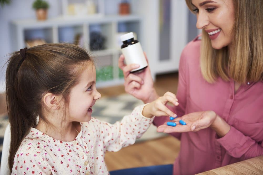 Young mum giving her little daughter the medicine