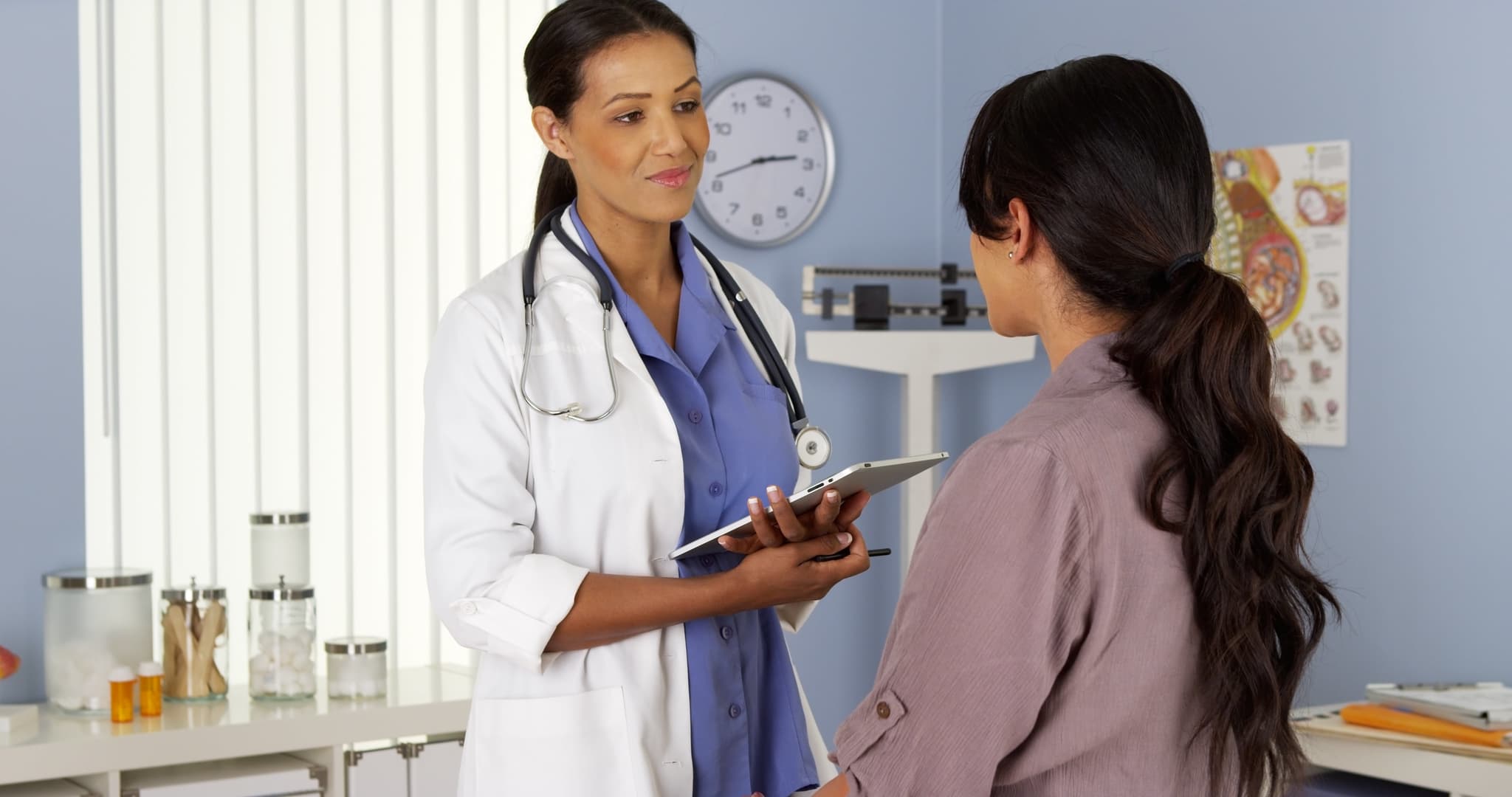 African American gynecologist talking to patient with tablet