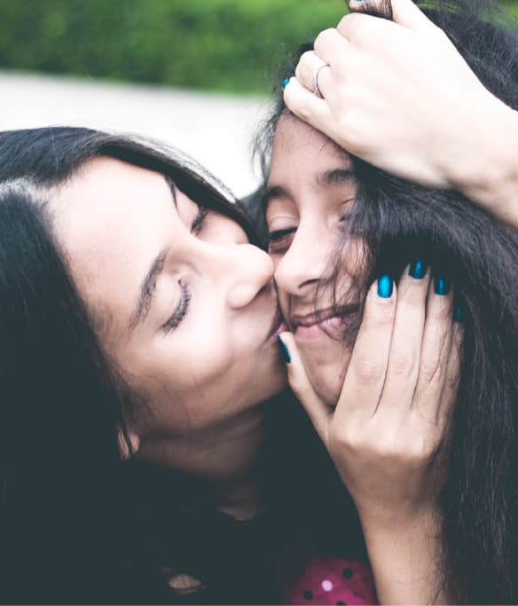 Woman kissing another woman's cheek