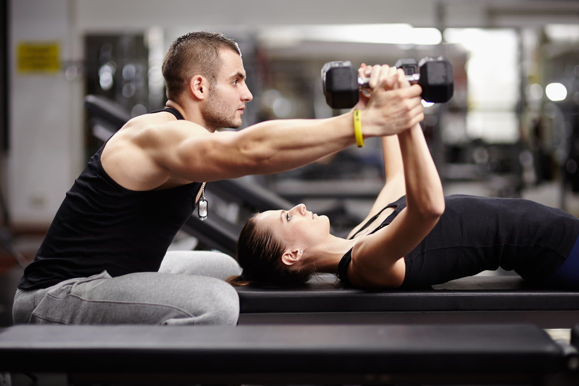 Picture of Personal trainer helping woman working with heavy dumbbells