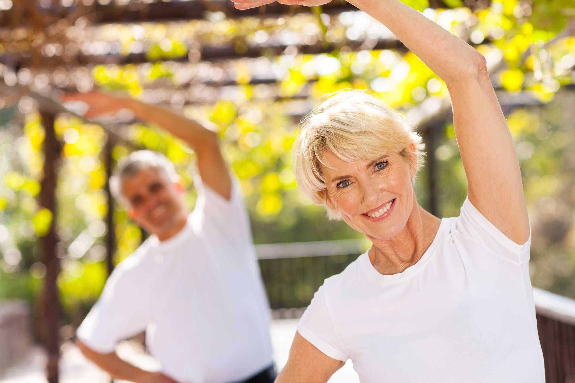 Picture of active senior woman exercising with husband outdoors