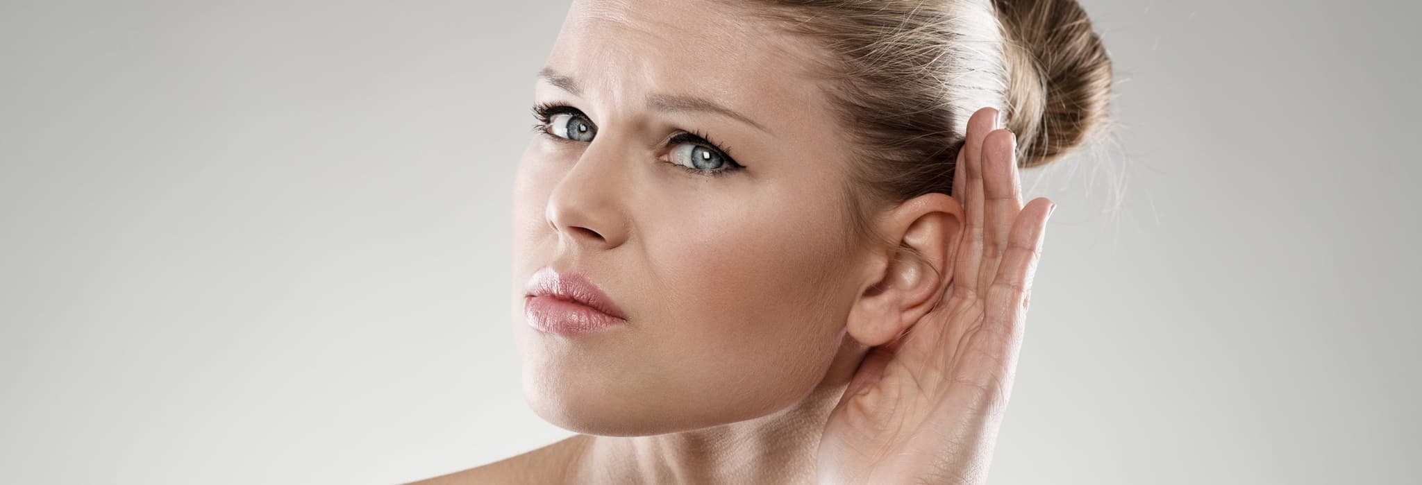 woman cupping ear to hear better