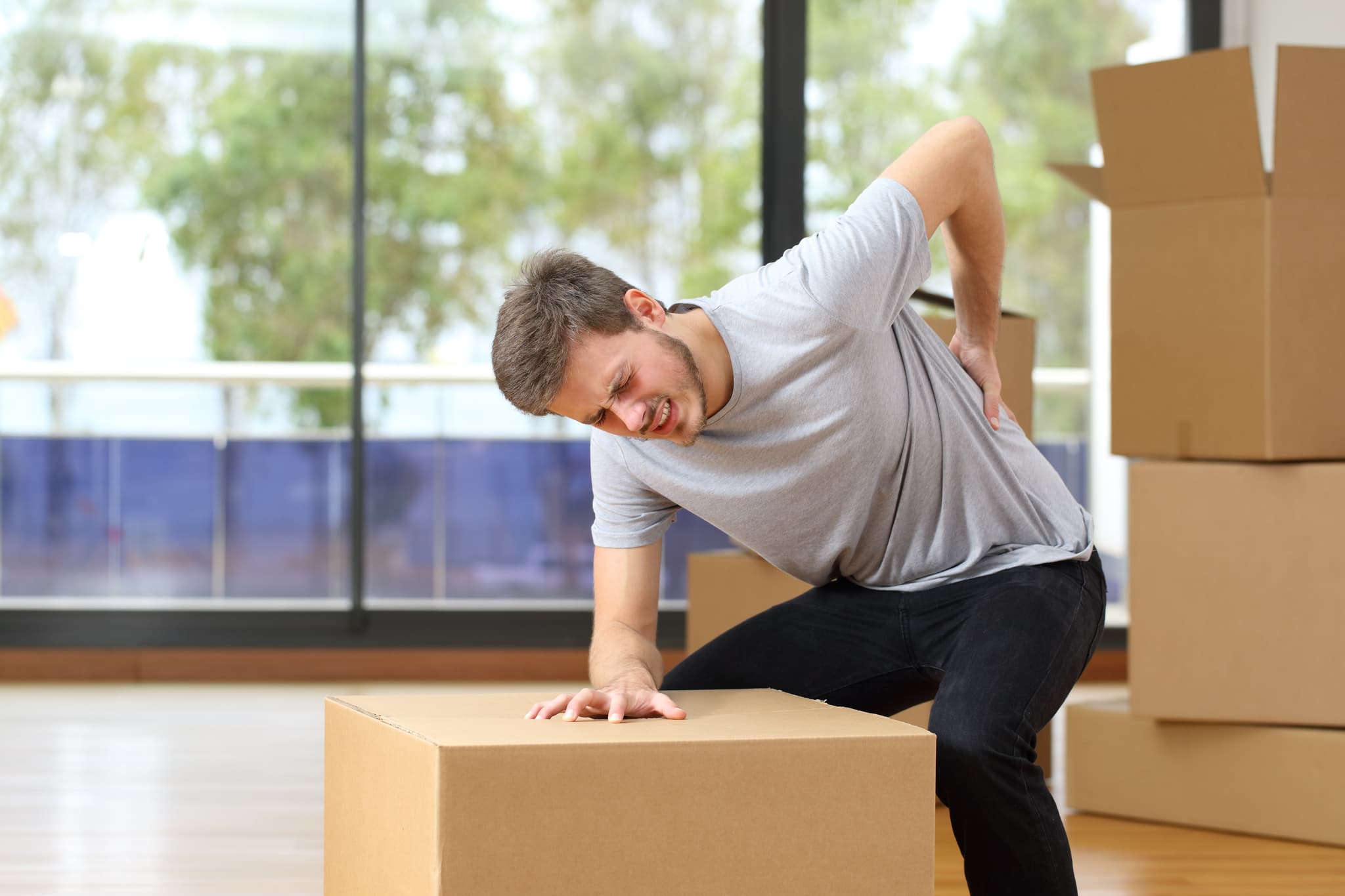Picture of Man suffering back ache moving boxes in his new house