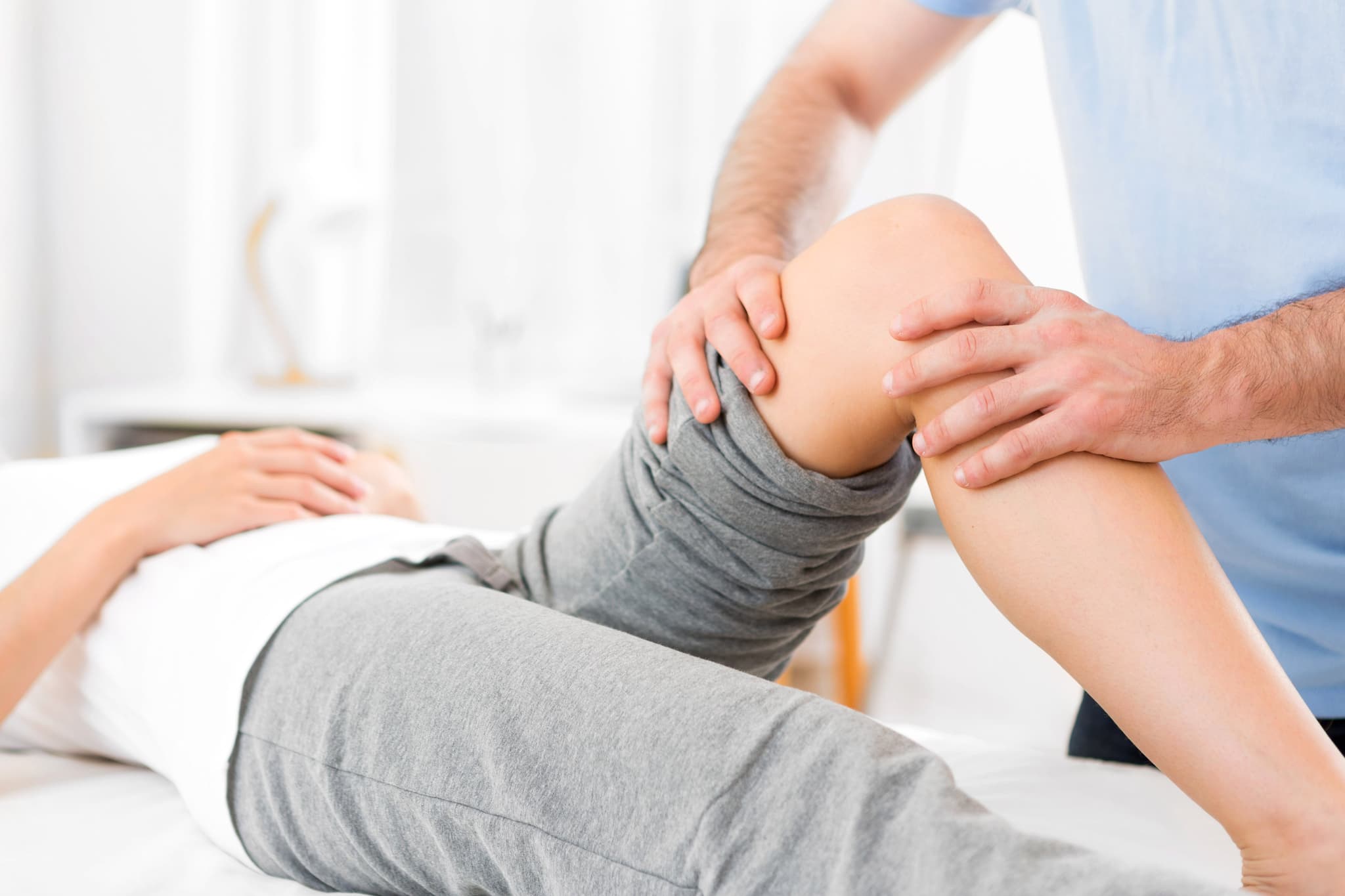 Young attractive woman being helped with physical therapy by physiotherapist