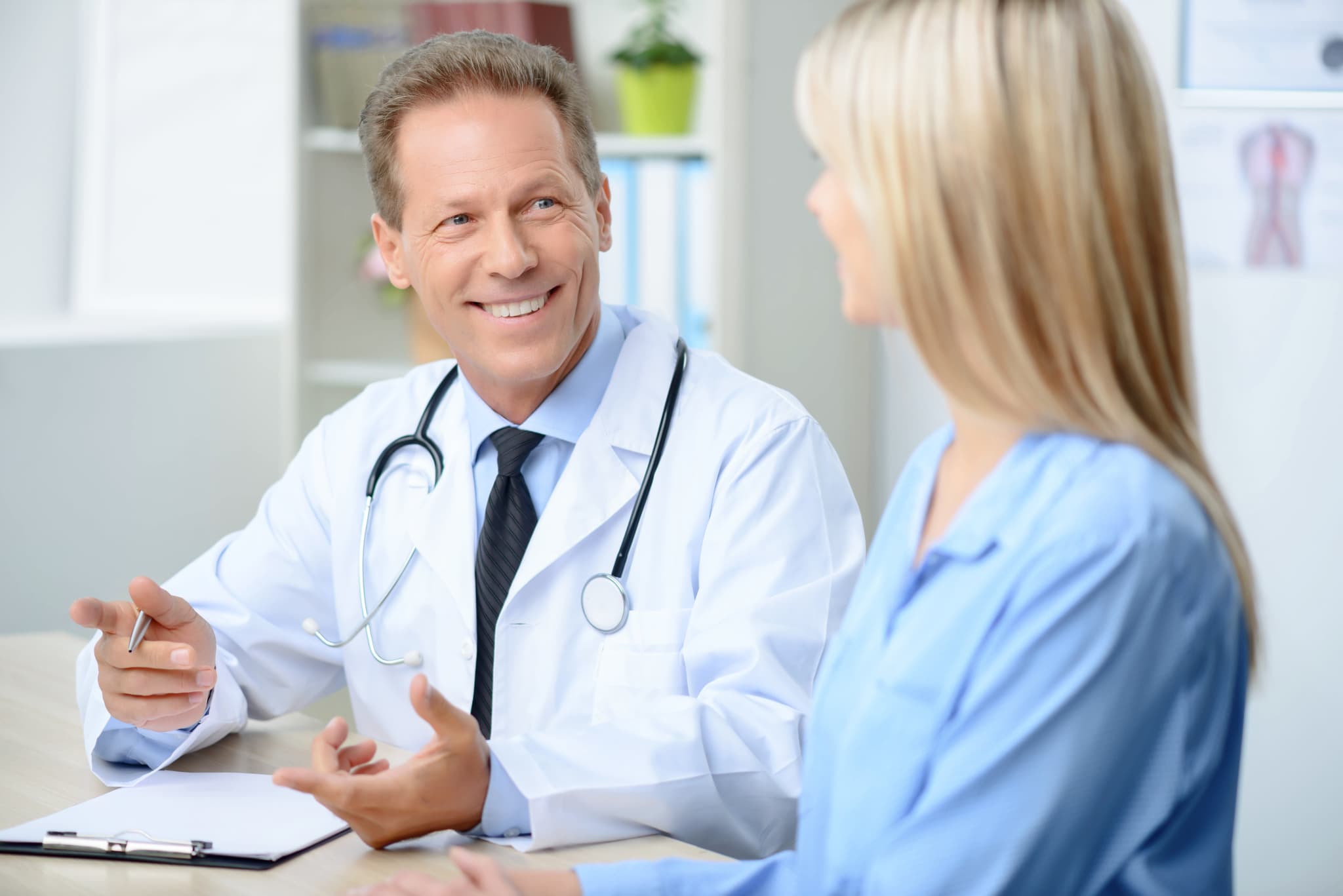 doctor with clipboard speaking with woman patient