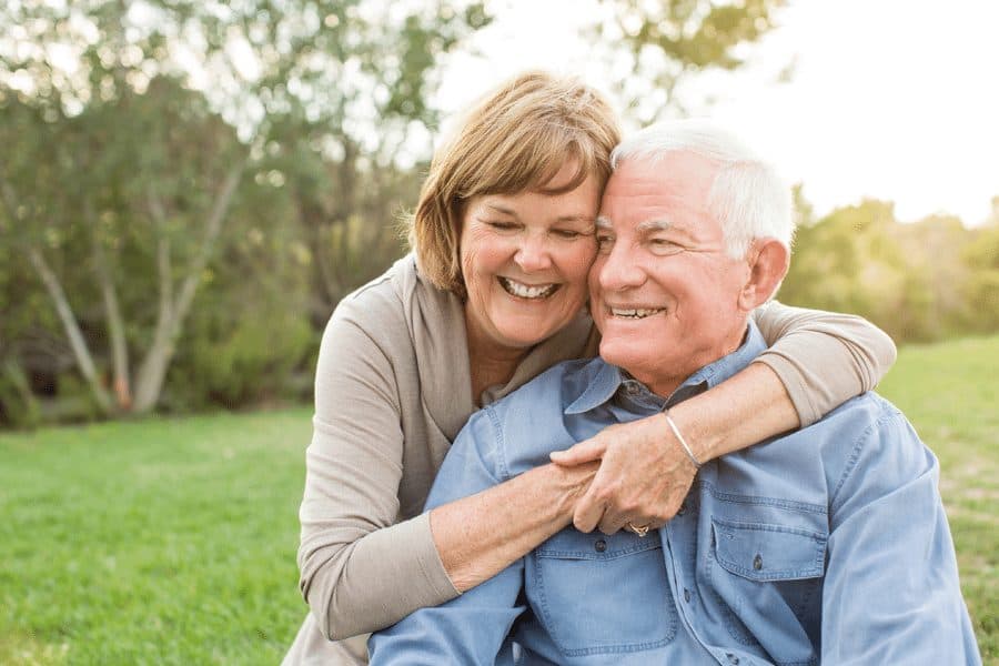 Picture of happy older couple hugging in park