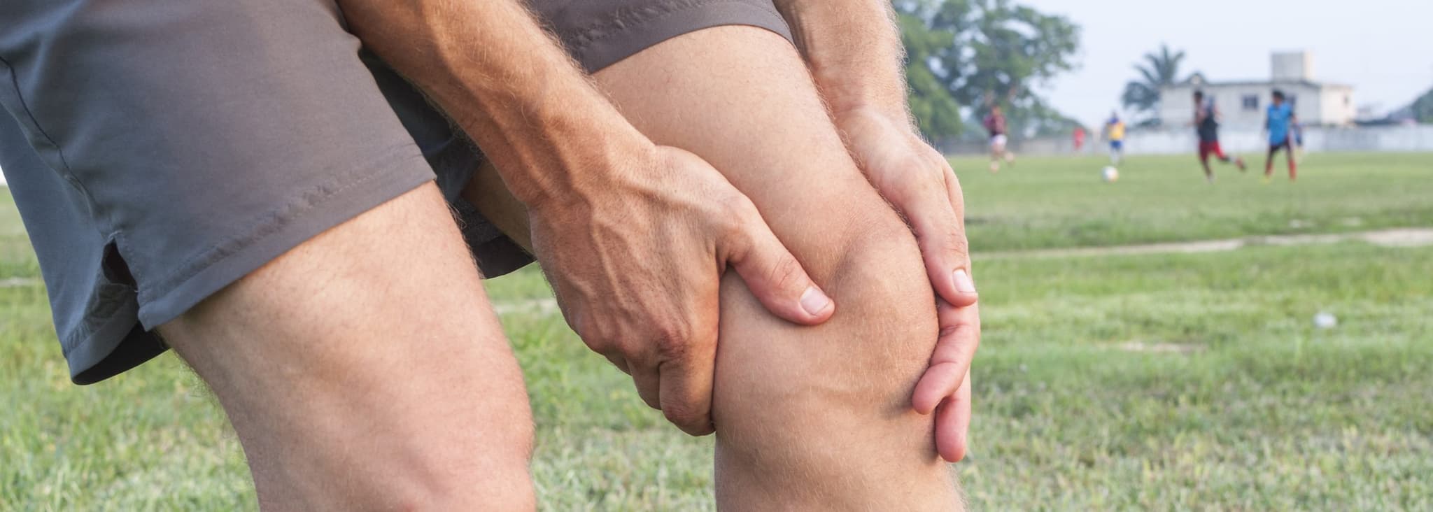 Picture of man clutching knee in pain on soccer field - MCL