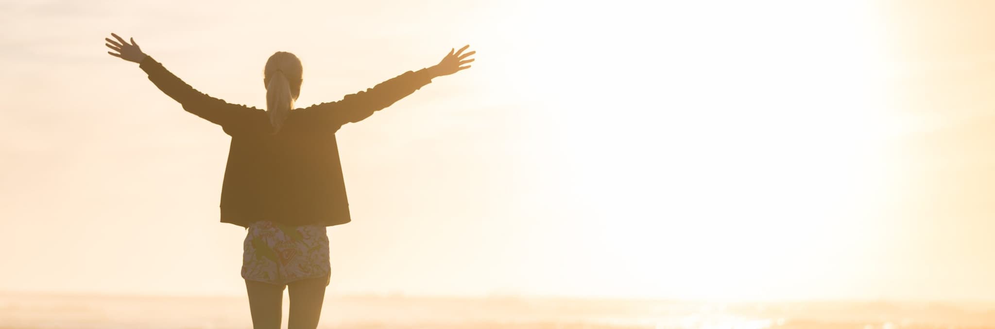 woman greeting sunrise by lake