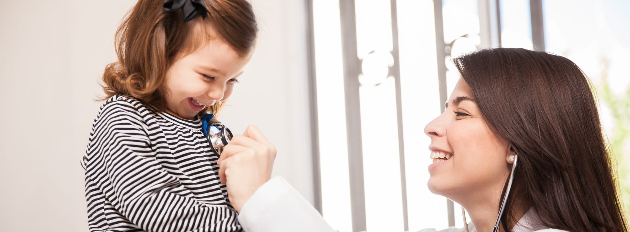 Picture of happy little child getting check up from smiling doctor