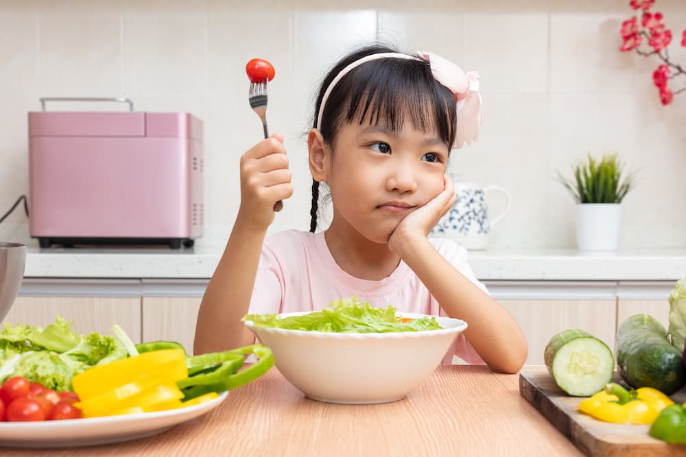 Picture of Asian Chinese little girl eating salad in the kitchen