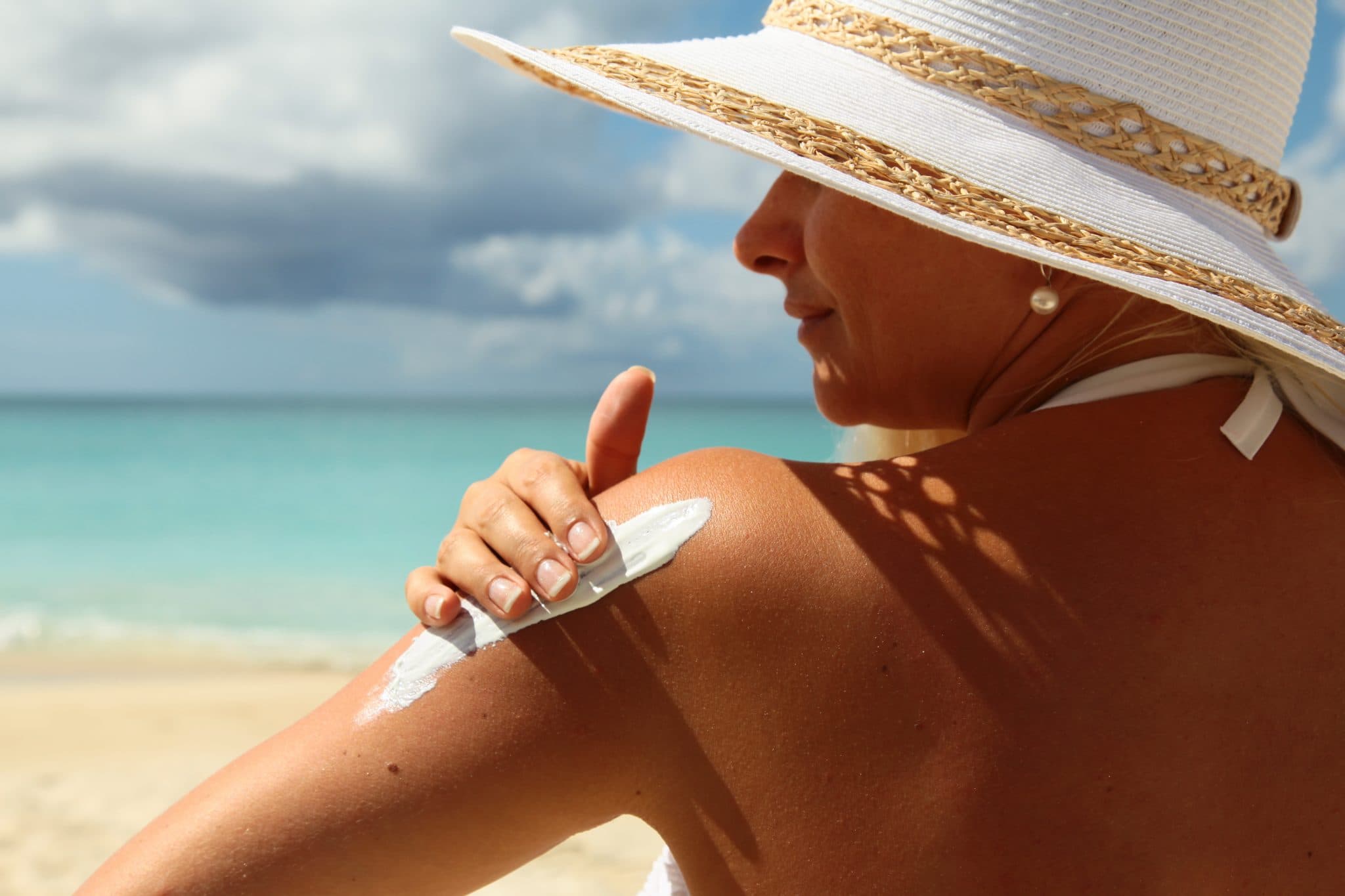 Picture of Young woman applying Suntan Lotion at the beach