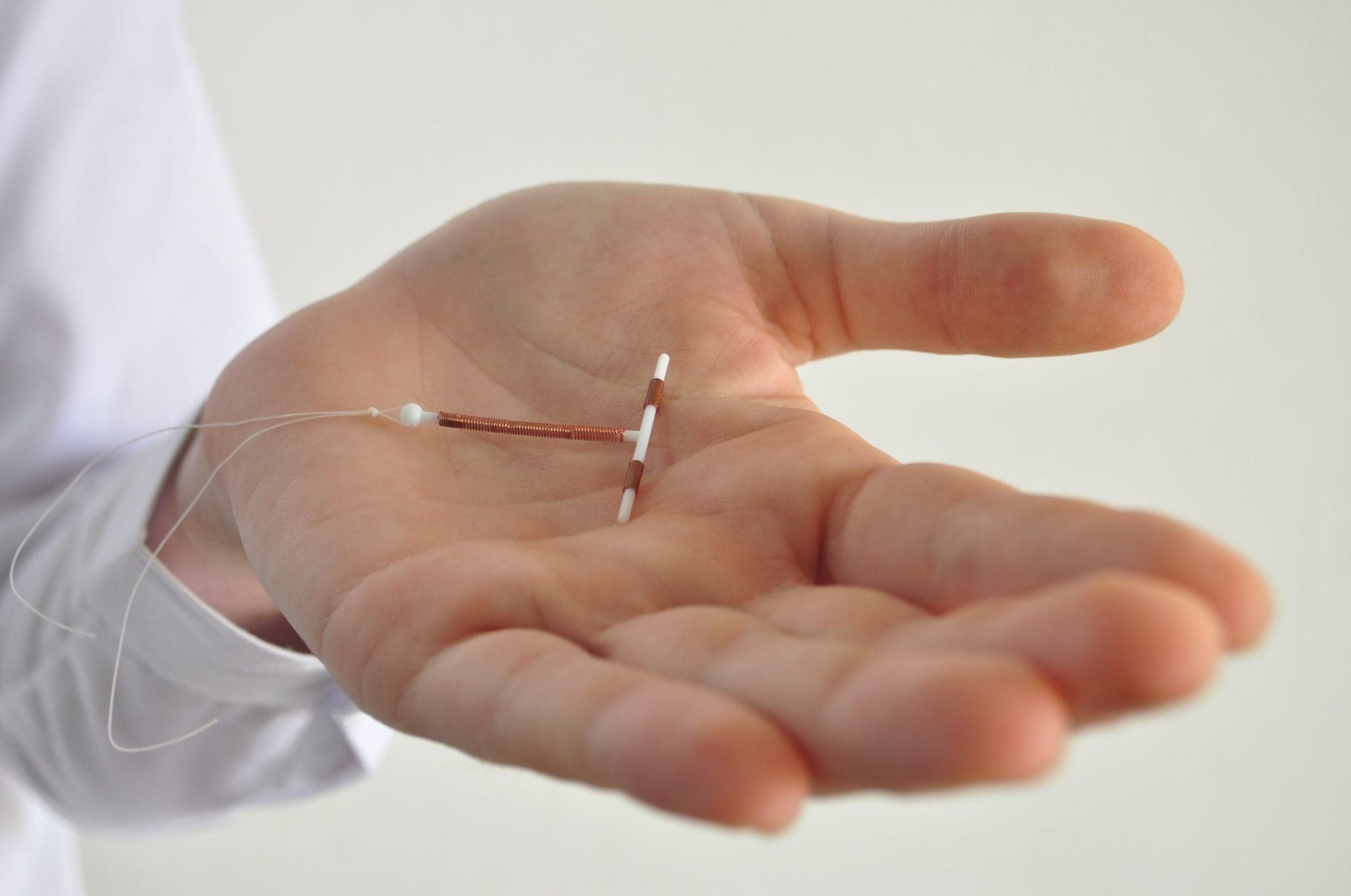 Picture of Holding an IUD birth control copper coil device in hand, used for contraception - side view