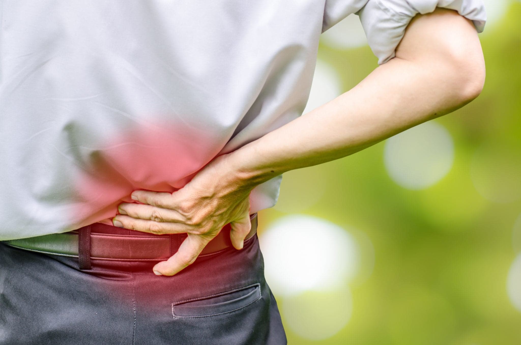 Picture of close up of a man holding his back in pain, monochrome photo with red as a symbol for the pain