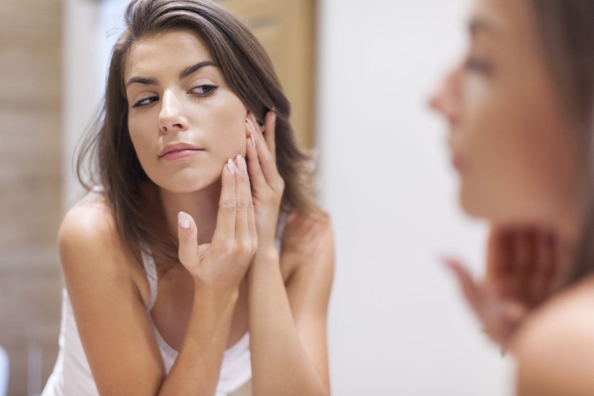 Woman taking care of her skin looking in the mirror