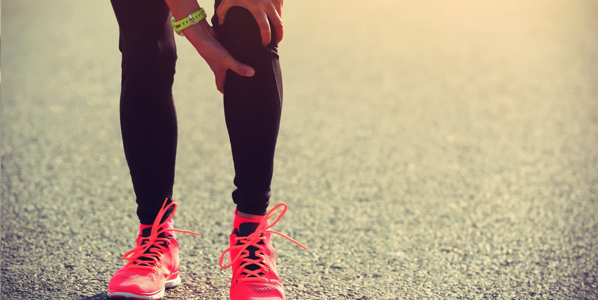woman runner hold her injured leg on road