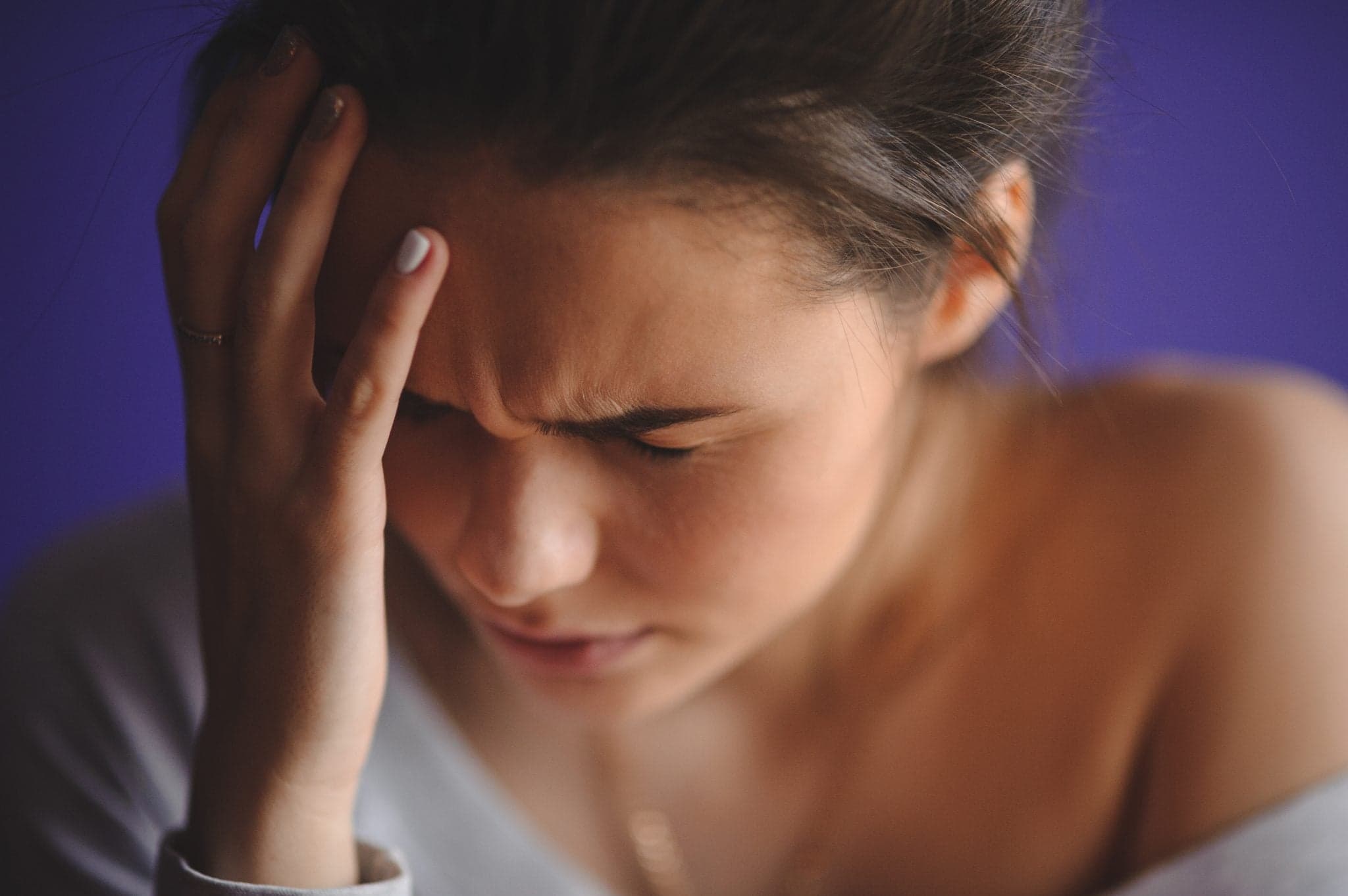 Teen woman with headache holding her hand to the head