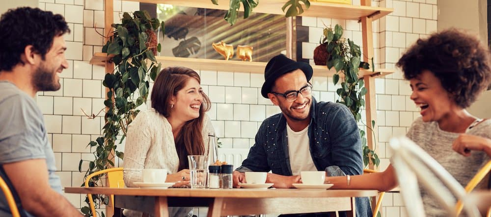 Young people having a great time in cafe. Friends smiling and sitting in a coffee shop, drinking coffee and enjoying together.