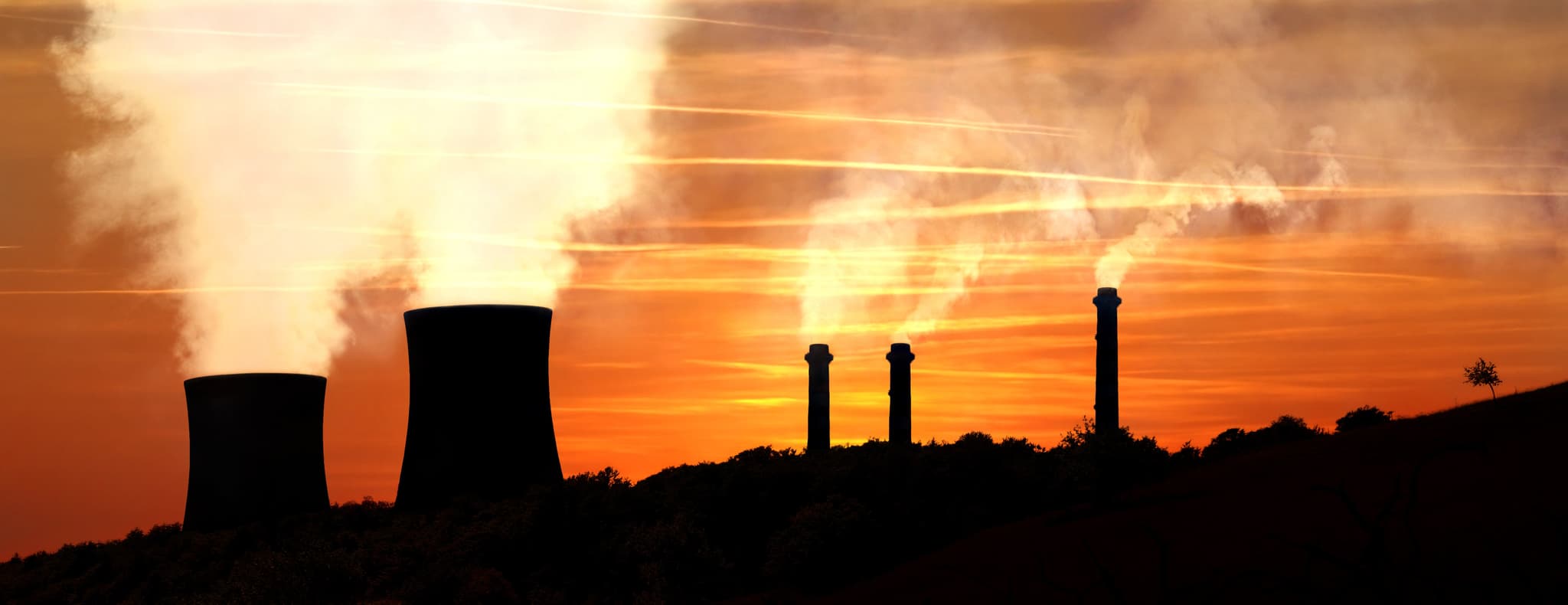 Power generating factories in the mountains at sunset backlight