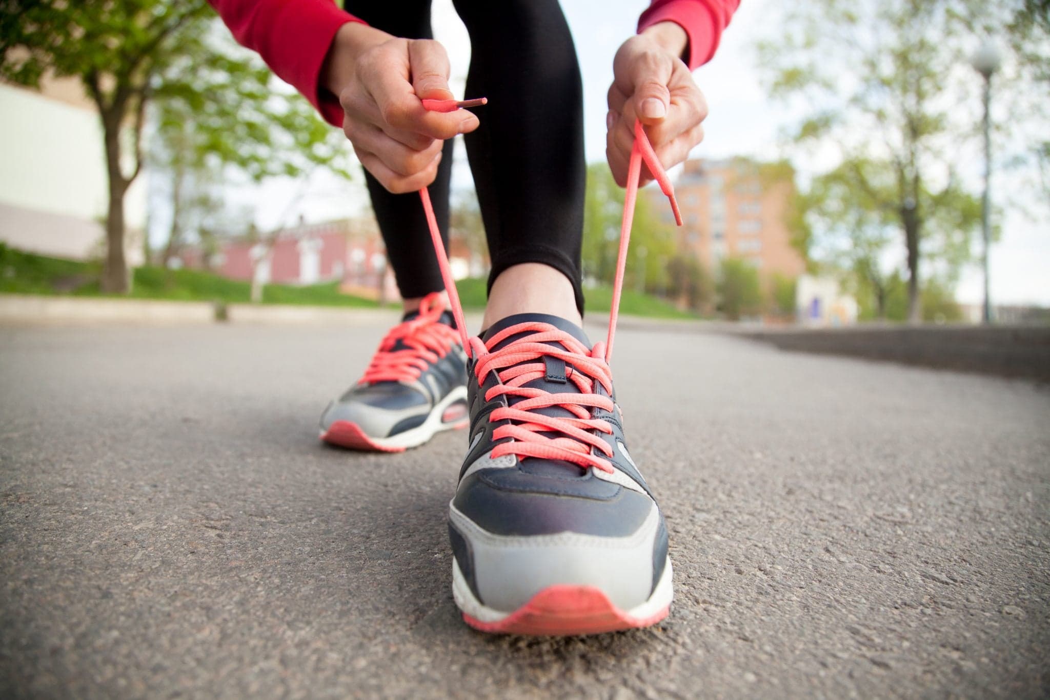 Picture of Sporty woman tying shoelace on running shoes before practice. Female athlete preparing for jogging outdoors. Runner getting ready for training. Sport active lifestyle concept. Close-up