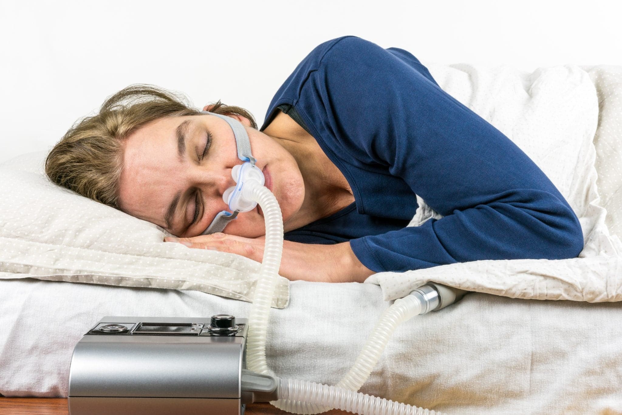 Image of Woman sleeping on her side with CPAP machine.